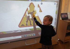 Dziewczynka pokazuje swoją pracę na tablicy interaktywnej